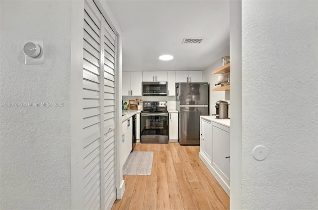 2055 SW 122nd Ave Unit 524, Miami, FL 33175 - kitchen featuring stainless steel appliances, a textured wall, white cabinetry, light countertops, and light wood-style flooring