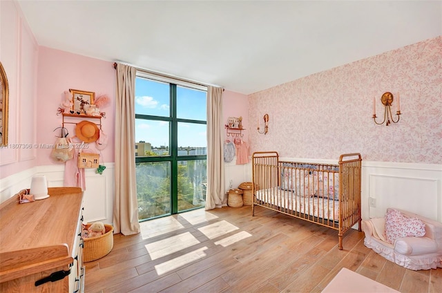2075 SW 122nd Ave Unit 517, Miami, FL 33175 - bedroom with wainscoting, wallpapered walls, wood finished floors, and a nursery area