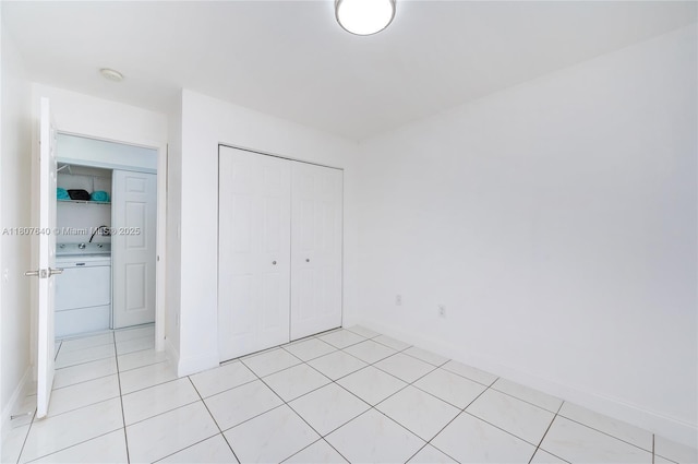 9021 NW 121st Ter Unit 85, Hialeah Gardens, FL 33018 - unfurnished bedroom with washer / dryer, baseboards, a closet, and light tile patterned floors