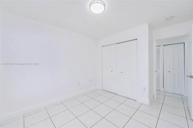 9021 NW 121st Ter Unit 85, Hialeah Gardens, FL 33018 - unfurnished bedroom featuring baseboards, light tile patterned floors, and a closet