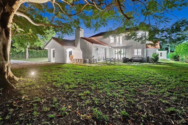321 SW 1st Ave, Boynton Beach, FL 33435 - rear view of house featuring a chimney, a yard, stucco siding, french doors, and a tiled roof