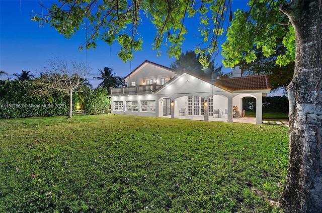 321 SW 1st Ave, Boynton Beach, FL 33435 - rear view of property featuring a balcony, a chimney, a lawn, stucco siding, and a tile roof