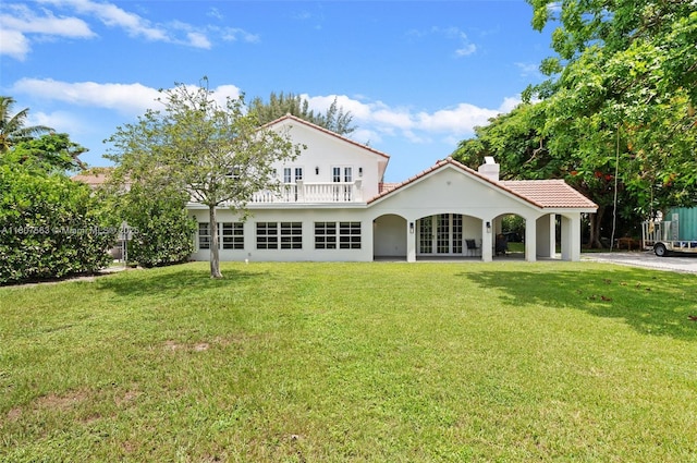 321 SW 1st Ave, Boynton Beach, FL 33435 - rear view of house with a balcony, a tile roof, a chimney, and a lawn