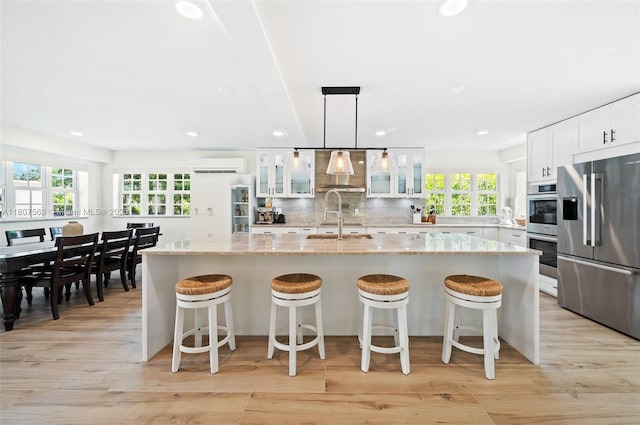 321 SW 1st Ave, Boynton Beach, FL 33435 - kitchen with stainless steel appliances, wall chimney range hood, tasteful backsplash, an AC wall unit, and glass insert cabinets