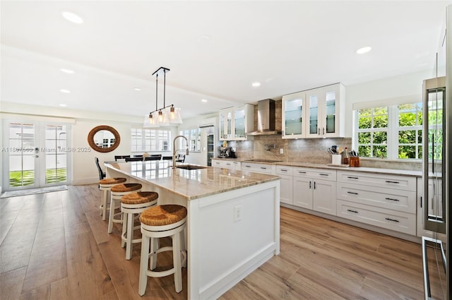 321 SW 1st Ave, Boynton Beach, FL 33435 - kitchen with wall chimney range hood, white cabinetry, recessed lighting, backsplash, and a kitchen island with sink