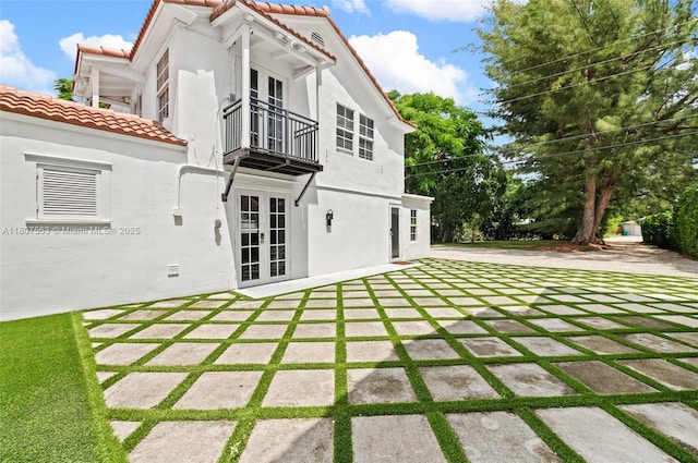 321 SW 1st Ave, Boynton Beach, FL 33435 - rear view of house with french doors, a balcony, a tiled roof, stucco siding, and a patio