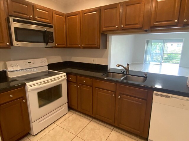 4291 NW 9th Ave Unit 202, Deerfield Beach, FL 33064 - kitchen featuring white appliances, a sink, light tile patterned floors, dark countertops, and brown cabinets