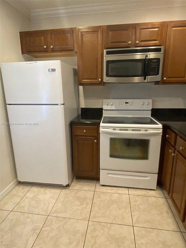 4291 NW 9th Ave Unit 202, Deerfield Beach, FL 33064 - kitchen with white appliances, crown molding, dark countertops, light tile patterned floors, and brown cabinets