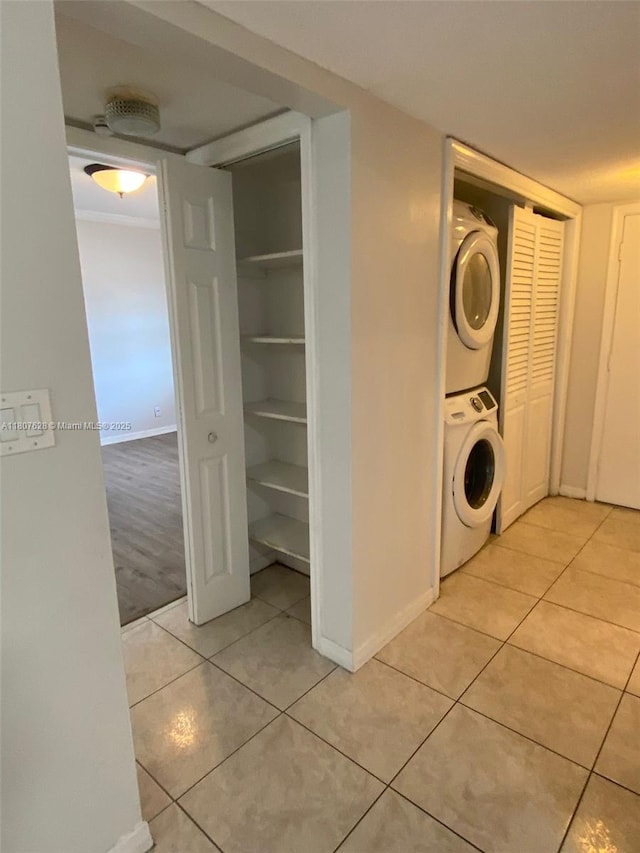 4291 NW 9th Ave Unit 202, Deerfield Beach, FL 33064 - washroom featuring stacked washer / dryer, light tile patterned floors, and baseboards