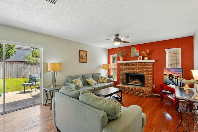 879 Matt Ln, Port Orange, FL 32127 - living room with ceiling fan, a textured ceiling, a brick fireplace, and wood finished floors