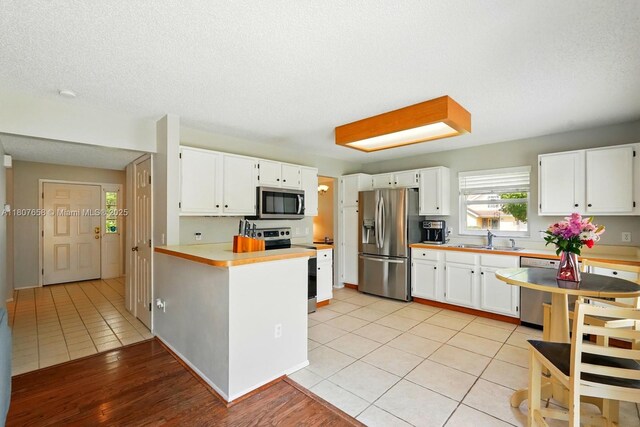 879 Matt Ln, Port Orange, FL 32127 - kitchen with stainless steel appliances, a sink, a peninsula, white cabinetry, and a textured ceiling