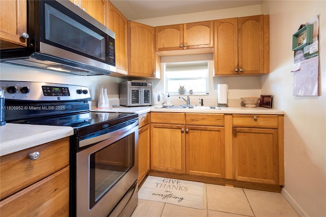 9823 S Hollybrook Lake Dr Unit 105, Pembroke Pines, FL 33025 - kitchen featuring appliances with stainless steel finishes, light countertops, light tile patterned floors, a sink, and brown cabinets