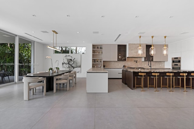 1379 N Venetian Way, Miami, FL 33139 - kitchen featuring a kitchen island, modern cabinets, tasteful backsplash, stainless steel double oven, and plenty of natural light