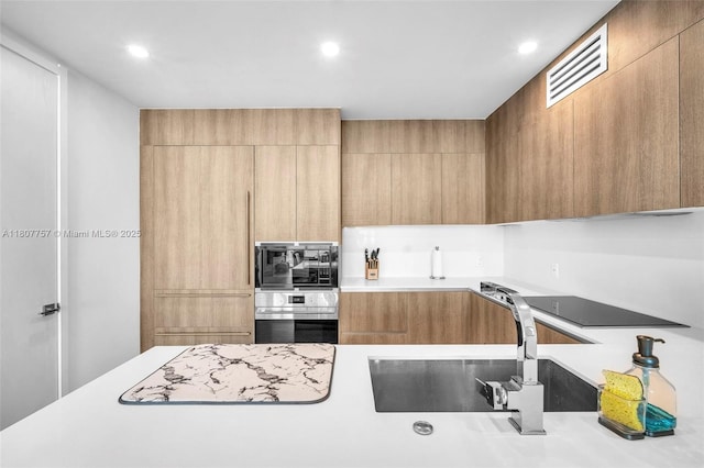 17550 Collins Ave Unit 704, Sunny Isles Beach, FL 33160 - kitchen featuring black appliances, modern cabinets, light countertops, recessed lighting, and a sink