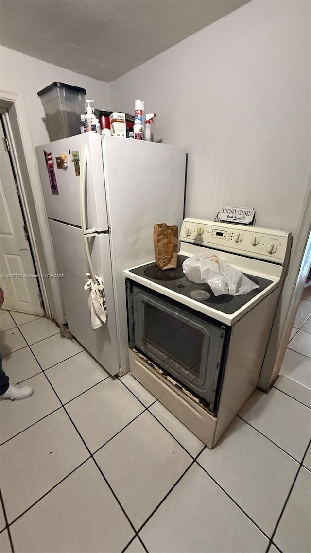 1230 NW 113th Ter, Miami, FL 33167 - kitchen with washer / clothes dryer, light tile patterned flooring, freestanding refrigerator, and range with electric cooktop