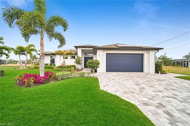 311 SE 14th St, Cape Coral, FL 33990 - prairie-style home featuring decorative driveway, solar panels, a front yard, and an attached garage