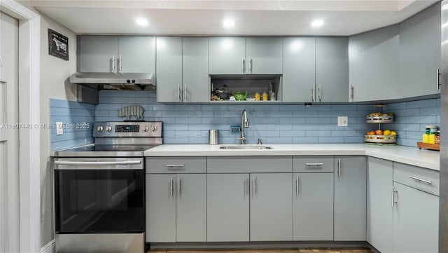 15 W 55th St, Hialeah, FL 33012 - kitchen with stainless steel electric stove, a sink, gray cabinetry, under cabinet range hood, and decorative backsplash