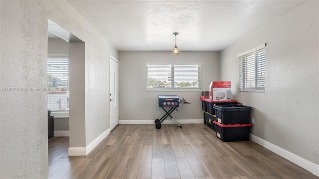 15 W 55th St, Hialeah, FL 33012 - dining area with wood finished floors, a textured wall, a textured ceiling, and baseboards