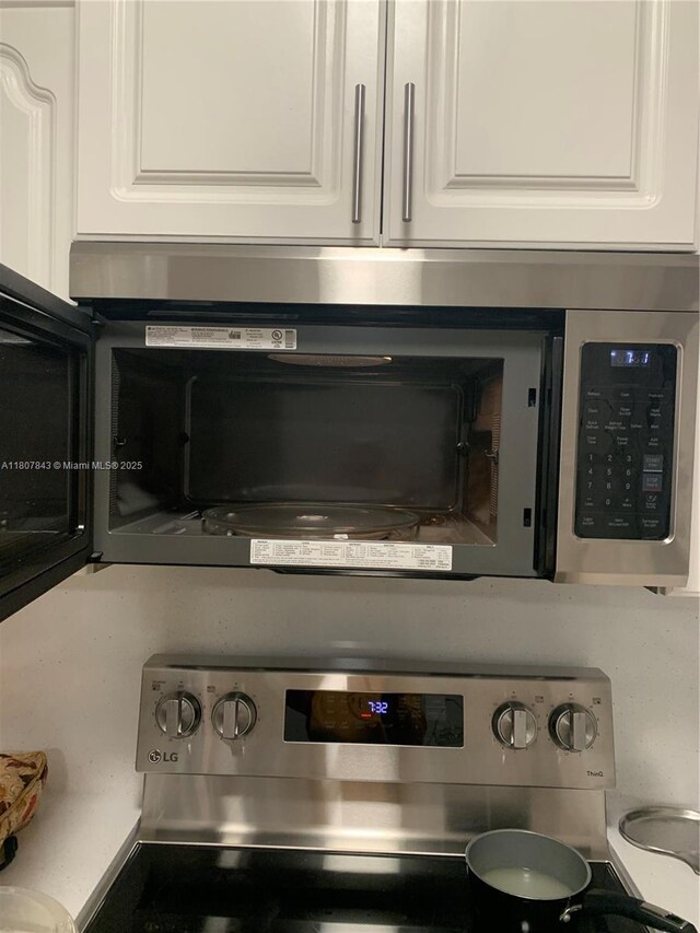 15029 SW 8th Ter, Miami, FL 33194 - kitchen view of black microwave, white cabinets, and stainless steel electric range