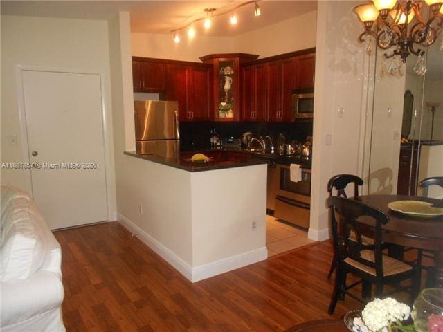 7707 Ashmont Cir Unit 214, Tamarac, FL 33321 - kitchen featuring appliances with stainless steel finishes, reddish brown cabinets, dark countertops, light wood-type flooring, and a peninsula