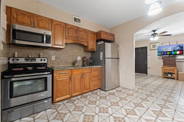 2655 NW 14th Ave, Miami, FL 33142 - kitchen with stainless steel appliances, ceiling fan, tasteful backsplash, a sink, and brown cabinetry
