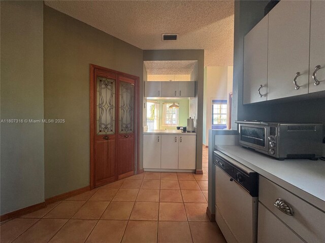 15569 N Miami Lakeway N Unit 204, Miami Lakes, FL 33014 - kitchen with dishwasher, light countertops, a textured ceiling, white cabinets, and light tile patterned floors