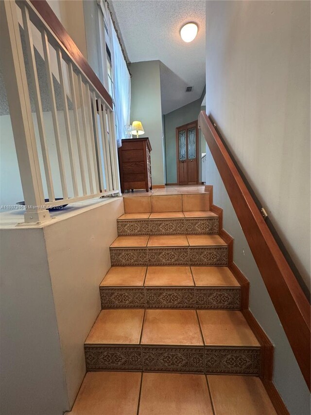 15569 N Miami Lakeway N Unit 204, Miami Lakes, FL 33014 - staircase with tile patterned flooring and a textured ceiling