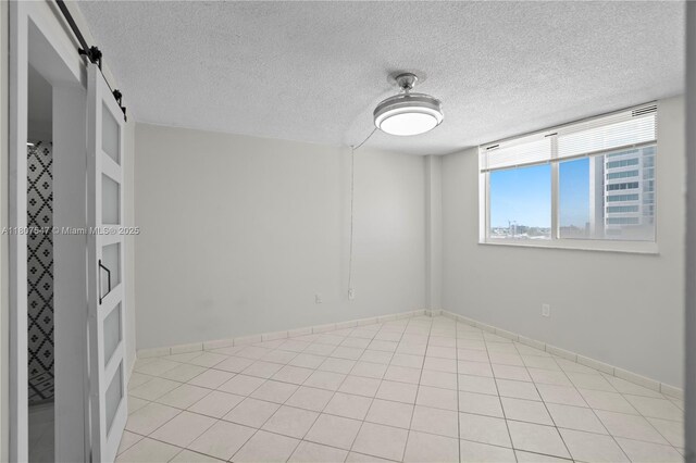 6969 Collins Ave Unit 707, Miami Beach, FL 33141 - unfurnished room with a barn door, a textured ceiling, baseboards, and light tile patterned floors