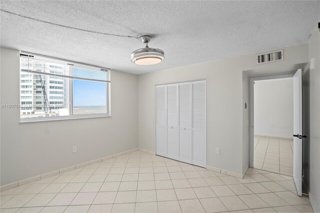 6969 Collins Ave Unit 707, Miami Beach, FL 33141 - unfurnished bedroom featuring a closet, light tile patterned floors, baseboards, and a textured ceiling