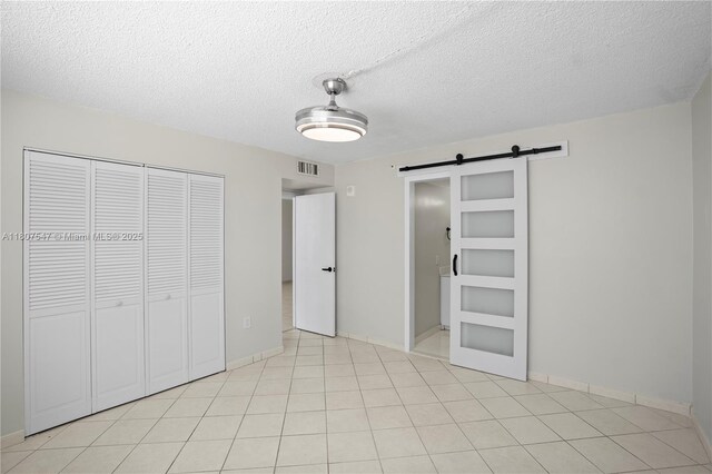 6969 Collins Ave Unit 707, Miami Beach, FL 33141 - unfurnished bedroom with a barn door, a closet, baseboards, and a textured ceiling