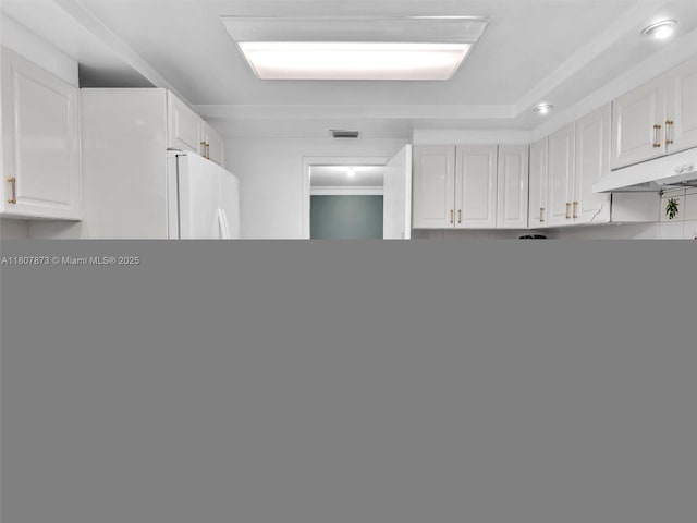 10155 Collins Ave Unit 408, Bal Harbour, FL 33154 - kitchen with under cabinet range hood, white fridge, and white cabinetry