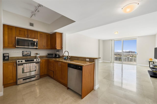 1755 E Hallandale Beach Blvd Unit 1604E, Hallandale Beach, FL 33009 - kitchen with appliances with stainless steel finishes, a sink, brown cabinets, track lighting, and open floor plan