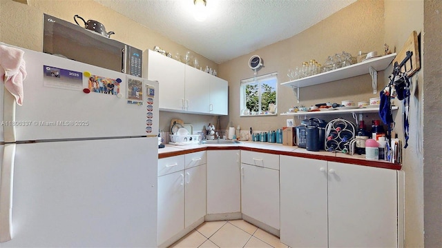 5301 SW 111th Ave, Miami, FL 33165 - kitchen with freestanding refrigerator, a textured wall, white cabinets, tile counters, and a textured ceiling