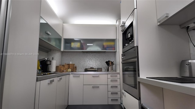 5005 Collins Ave Unit 212, Miami Beach, FL 33140 - kitchen featuring oven, decorative backsplash, white cabinetry, and built in microwave
