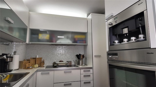 5005 Collins Ave Unit 212, Miami Beach, FL 33140 - kitchen featuring oven, decorative backsplash, white cabinets, black electric stovetop, and light countertops