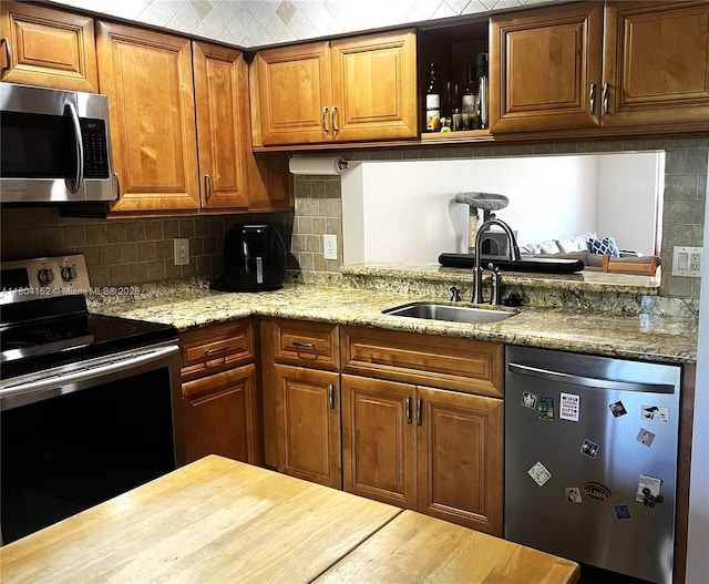 9955 NW 56th Pl, Coral Springs, FL 33076 - kitchen with appliances with stainless steel finishes, a sink, backsplash, brown cabinetry, and light stone countertops
