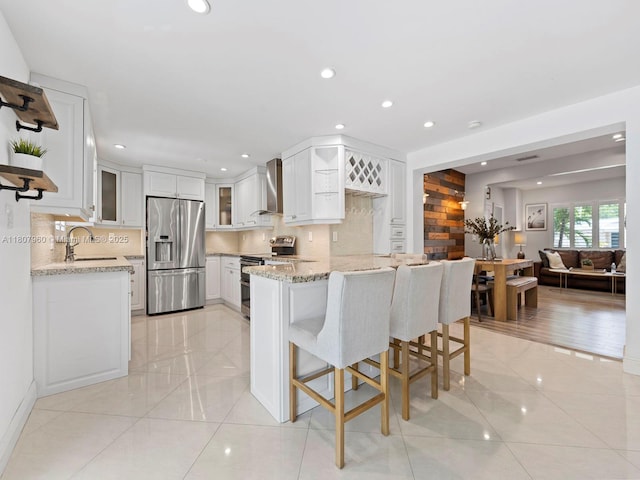 5930 SW 13th Ter, West Miami, FL 33144 - kitchen featuring stainless steel appliances, a sink, a peninsula, wall chimney range hood, and light tile patterned floors