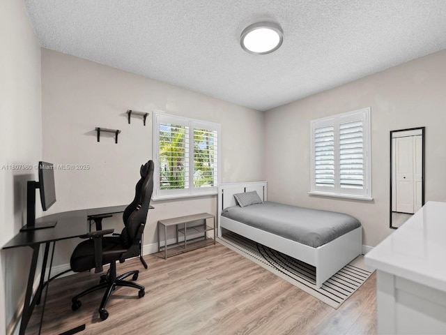 5930 SW 13th Ter, West Miami, FL 33144 - bedroom featuring light wood finished floors, a textured ceiling, a desk, and baseboards
