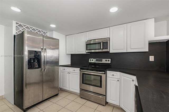 555 NE 15th St Unit 603, Miami, FL 33132 - kitchen featuring stainless steel appliances, white cabinets, dark countertops, light tile patterned floors, and recessed lighting