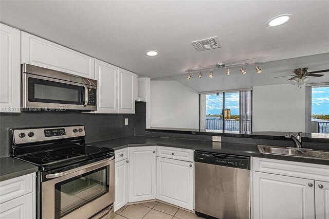 555 NE 15th St Unit 603, Miami, FL 33132 - kitchen featuring stainless steel appliances, a sink, dark countertops, light tile patterned flooring, and white cabinets