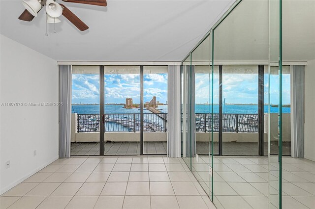 555 NE 15th St Unit 603, Miami, FL 33132 - empty room featuring a wall of windows, a water view, ceiling fan, tile patterned floors, and baseboards