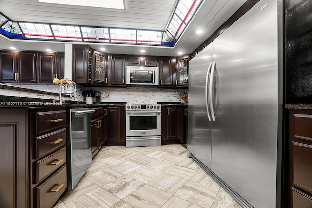 101 SW 96th Ter Unit 204, Plantation, FL 33324 - kitchen featuring stainless steel appliances, dark countertops, decorative backsplash, dark brown cabinets, and glass insert cabinets