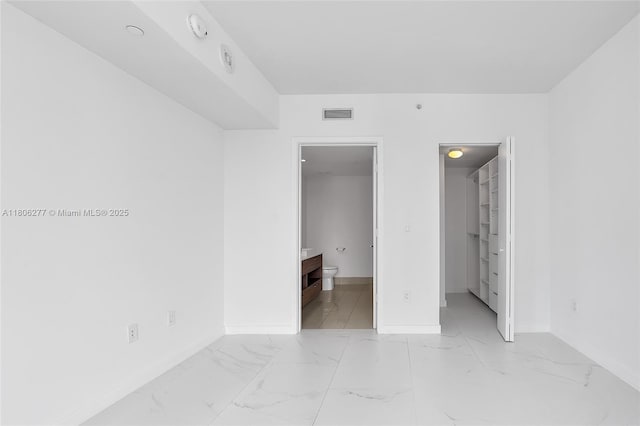 1300 S Miami Ave Unit 3211, Miami, FL 33130 - unfurnished bedroom with baseboards, a walk in closet, connected bathroom, and light marble finish floors