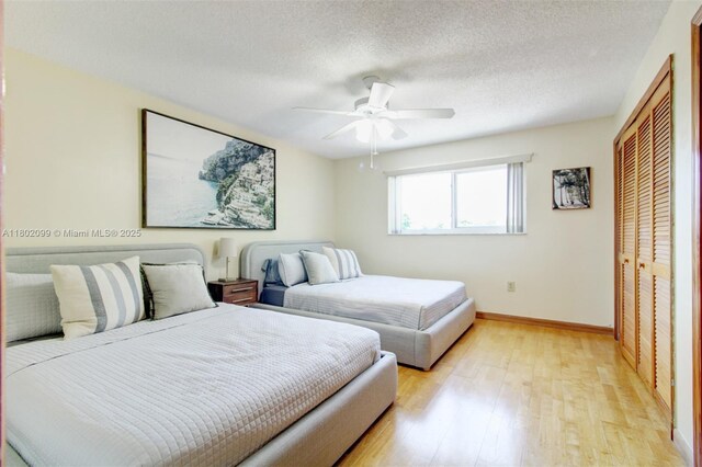 7891 SW 9th Ter, Miami, FL 33144 - bedroom featuring light wood-style flooring, a closet, baseboards, ceiling fan, and a textured ceiling