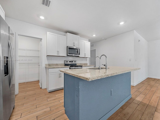 501 NE 6th Ct, Florida City, FL 33034 - kitchen featuring stainless steel appliances, a sink, light wood-type flooring, white cabinets, and recessed lighting