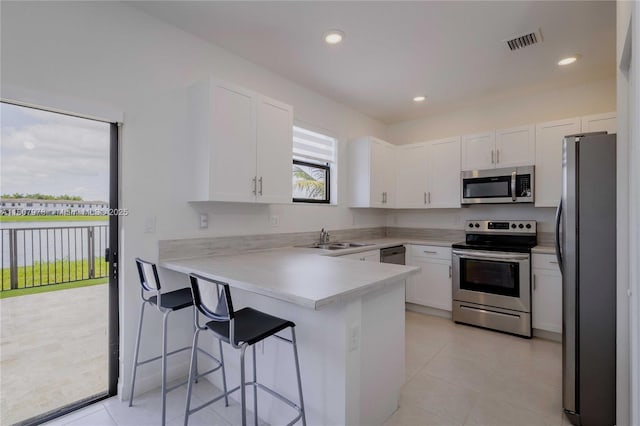 10260 SW 228th Ter Unit 10260, Miami, FL 33190 - kitchen featuring appliances with stainless steel finishes, a peninsula, a sink, white cabinets, and recessed lighting