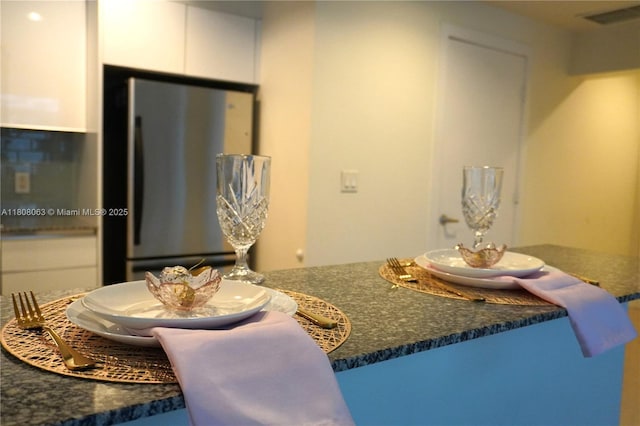 1050 Brickell Ave Unit 202, Miami, FL 33131 - kitchen featuring freestanding refrigerator, white cabinetry, and dark stone counters