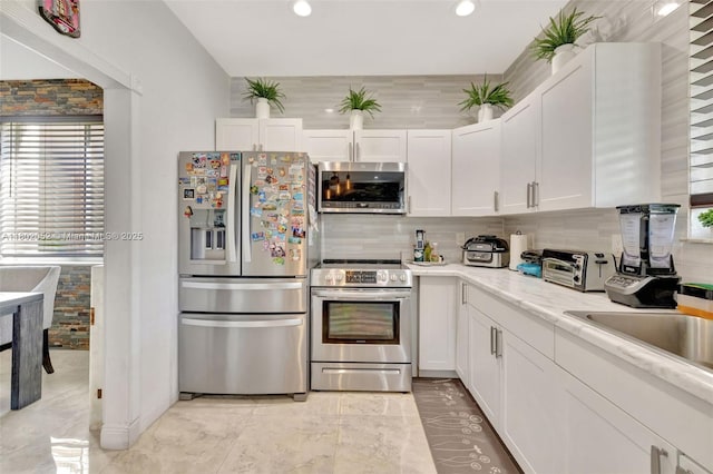 1317 Majesty Ter, Weston, FL 33327 - kitchen with appliances with stainless steel finishes, white cabinetry, decorative backsplash, light countertops, and plenty of natural light