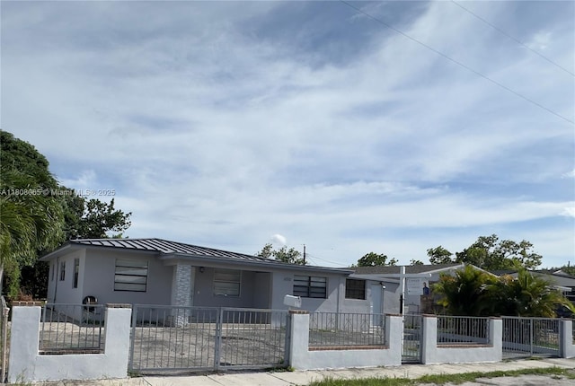 650 E 55th St, Hialeah, FL 33013 - view of front of home with stucco siding, a standing seam roof, a metal roof, and a fenced front yard