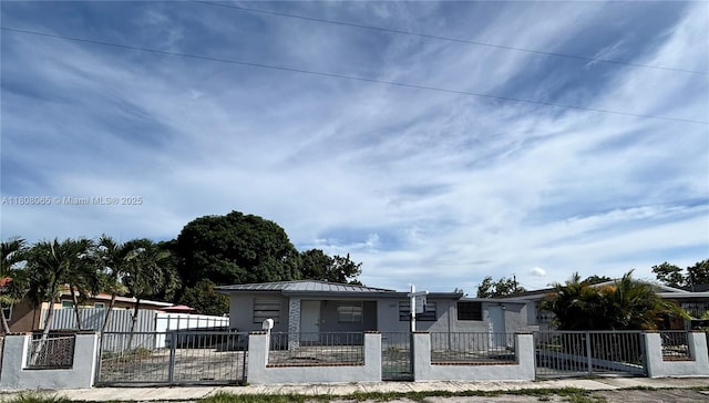 650 E 55th St, Hialeah, FL 33013 - view of front of house with a standing seam roof, a metal roof, a fenced front yard, and stucco siding